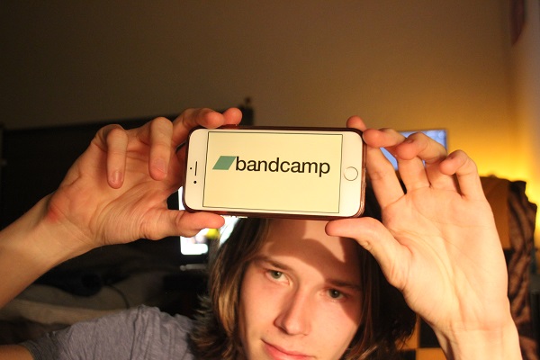 Me holding a phone with bandcamp on it